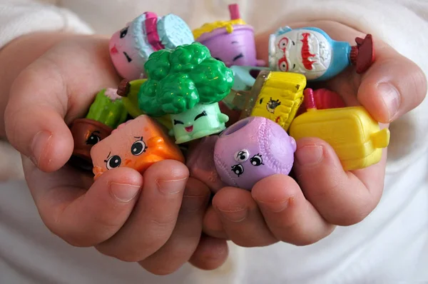 年轻女孩持有 Shopkins 的一系列小的可收集的玩具 由驼鹿玩具制造 根据杂货店的物品每个塑料图有一个可辨认的面孔和唯一的名字 — 图库照片