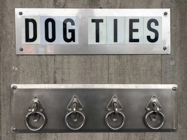 挂在音乐会墙上的四个金属环上的狗领带标志 — 图库照片