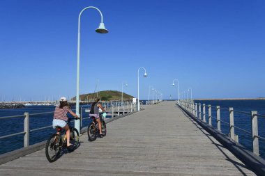 İki kadın cyling Coffs Harbour iskelesi yeni Güney Walse Australi üzerinde
