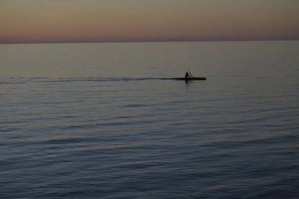 Homme pagayant en kayak avec coucher de soleil spectaculaire — Photo