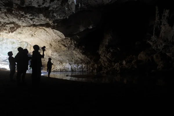 Sylwetka ludzi wędrówki w podziemnej jaskini — Zdjęcie stockowe
