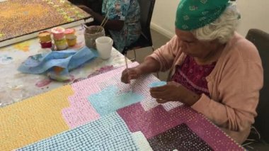 PORT HEDLAND, WA - 20 SEP 2019: Avustralya yerlisi yetişkin kadınlar nokta boyama. Avustralya yerlileri tuvale konulmadan önce toprak üzerine kutsal seremoni tasarımları çiziyorlardı.