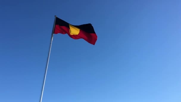 Αυστραλιανή Σημαία Των Ιθαγενών Κύμα Κάτω Από Καθαρό Γαλάζιο Ουρανό — Αρχείο Βίντεο