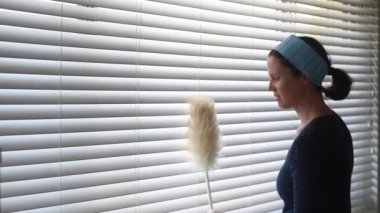 Yetişkin kadın (30-40 yaş) temizleyici pencere temizleme panjurları. Gerçek insanlar. Boşluğu kopyala