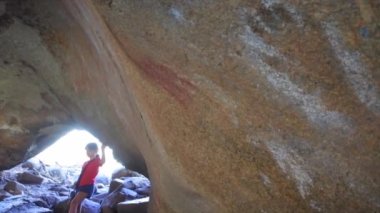 Genç Avustralyalı turist (9-10 yaş) Hyden Batı Avustralya yakınlarındaki Mulkas Mağarası 'ndaki antik Avustralya yerlisi kaya resmine bakıyor.