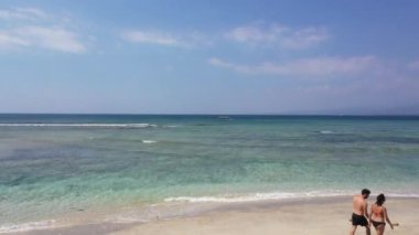 Gili Air Island Endonezya 'nın kumlu sahillerinde yürüyen turist çiftlerin insansız hava aracı görüntüsü. Gili Adaları balayındakiler için çok popüler turistik yerler..