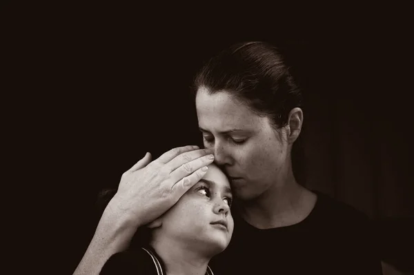 Mother Comforting Her Young Daughter Sitting Dark Isolated Black Background — Stock Photo, Image