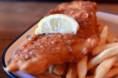 Bir tabak taze limonla servis edilen ev yapımı balık ve patates kızartması..