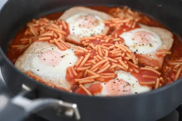 意大利面 烤好的面包片 配上一面阳光明媚的鸡蛋 放在一个煎锅里烹调 — 图库照片