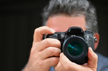 Siyah arka planda izole edilmiş bir kamerayla fotoğraf çeken adam..