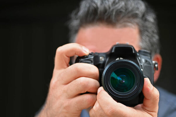 Man photographer photographing with a camera isolated on black background.