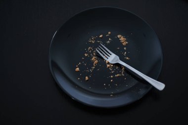 Ekmek kırıntıları olan boş siyah tabağın üstü.