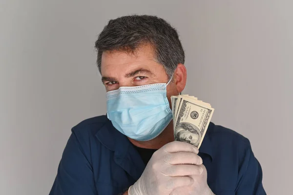 Greedy adult man wearing a face mask holding Federal Reserve Bank Notes payments looking at camera.