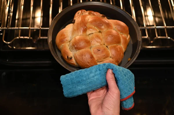ロシュ ハシャナーのために特別に焼き上げられたオーブンから甘いチャラパンを取るユダヤ人女性の視点ユダヤ人の新年の休日 — ストック写真