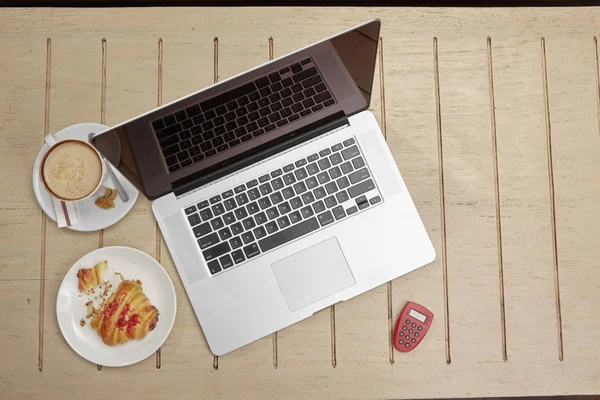 咖啡桌上的笔记本电脑和小吃 — 图库照片