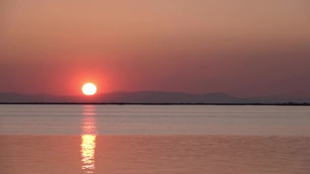 它显示毛茸茸的云彩缓缓向夕阳西下移动 太阳的金黄色光芒反射在完全平静的海洋中 — 图库视频影像
