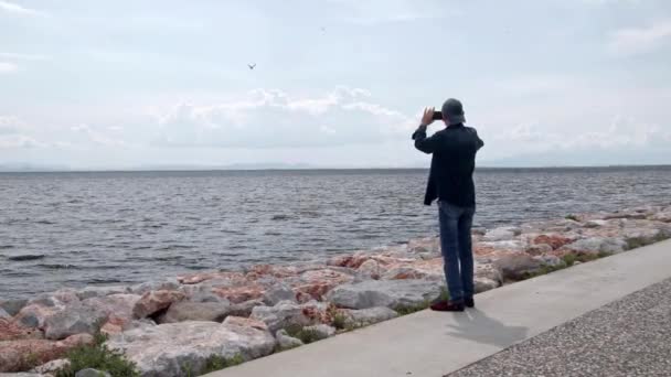 Ein Mann Fotografiert Das Meer Mit Seinem Handy — Stockvideo