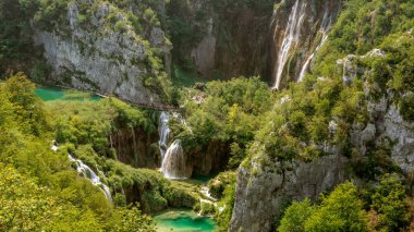 Yaz mevsiminde Plitvice gölleri ve arka planda büyük şelaleler.