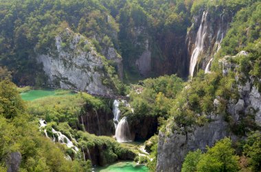 Yaz mevsiminde Plitvice gölleri ve arka planda büyük şelaleler.