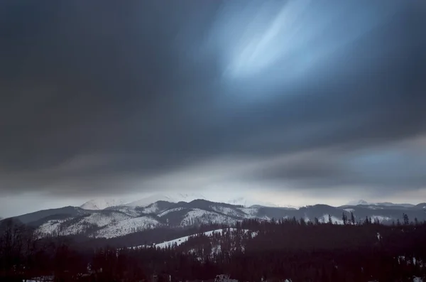 Longa exposição das montanhas cobertas de neve e um céu nublado . — Fotografia de Stock