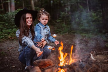 Anne ve kızı ormanda kamp ateşi üzerinde Lokum Şekerleme kızartma. İlkbahar veya sonbaharda kamp
