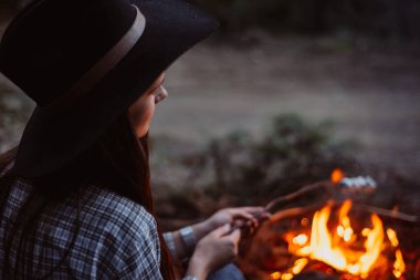 Gezgin kız fry Marshmallow ormanın içinde yanıyor. Akşam ışığı.