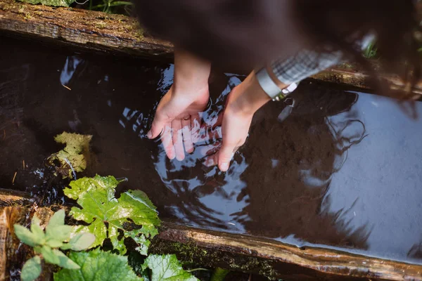 Kız kaynak suyu onun elinde yıkıyor.