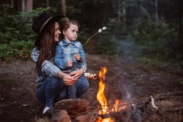 Anne ve kızı ormanda kamp ateşi üzerinde Lokum Şekerleme kızartma. İlkbahar veya sonbaharda kamp