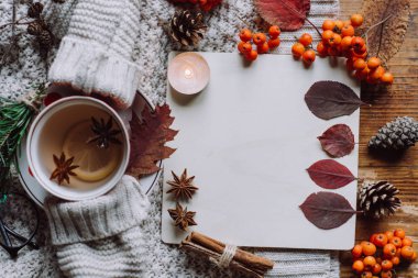 Şık düz ahşap arka plan üzerinde görünümü ekose desenli kazak ve sonbahar yaprakları çay ile yatıyordu. Sonbahar ya da kış konsepti. 