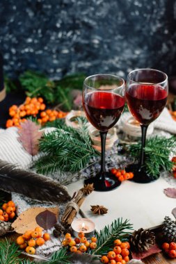 Mulled şarap gözlük, kırmızı meyveler, diken diken ve ahşap masa sonbahar dallarda. Sonbahar ya da kış konsepti.
