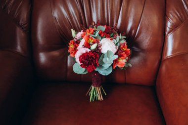 Düğün buket kırmızı bir sandalye üzerinde duran kırmızı ve beyaz çiçekli