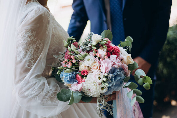 wedding bouquet from red and white flowers in brides hands