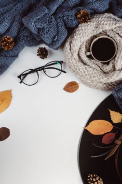 Sonbahar yaprakları ve tartan düz yatıyordu görünümünü fincan kahve, gözlük ve şapka beyaz zemin üzerine mavi kazak dokulu. Sonbahar konsepti.