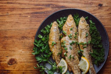 Ahşap masa üzerinde bir tabak kızarmış balık