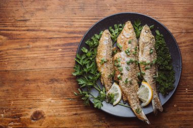 Ahşap masa üzerinde bir tabak kızarmış balık