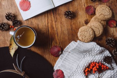 Çay ile ahşap arka plan üzerinde düz yatıyordu görünümü ekose desenli kazak ve sonbahar yaprakları. Sonbahar ya da kış konsepti.