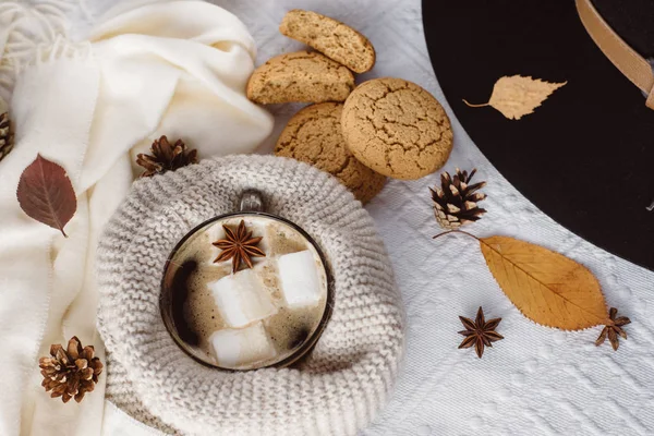 Autumn and Winter composition. Hot coffee with marshmallows, scarf, cookies, hat, bumps and autumn leaves. Flat lay, top view