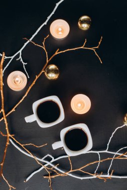 Kış kompozisyon. İki bardak kahve, dalları, mumlar ve karanlık bir arka plan üzerinde Noel oyuncaklar. düz lay
