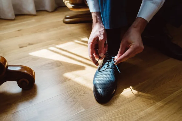 adam bir sandalyede oturuyor ve telleri Ayakkabı bağlama.