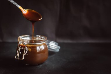 Dökülen karanlık eritilmiş çikolata üzerinde izole koyu arka plan. 