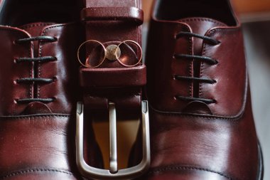 Erkek ayakkabı, kemer ve alyans cam sandalye üzerinde. Damadın düğün detayları