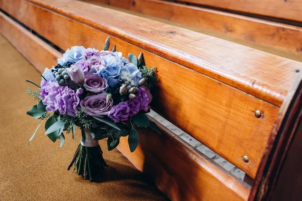 wedding bouquet of purple and blue flowers on wooden furniture