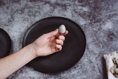 Kadın küçük çiğ Bıldırcın yumurta elele geziyor. Karanlık beton arka plan, üstten görünüm