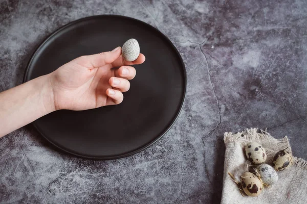 Kadın küçük çiğ Bıldırcın yumurta elele geziyor. Karanlık beton arka plan, üstten görünüm