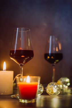 Tatil kompozisyon bardak kırmızı şarap, mumlar ve çelenk karanlık bir arka plan üzerine yapılmış
