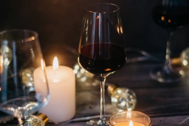 Tatil kompozisyon bardak kırmızı şarap, mumlar ve çelenk karanlık bir arka plan üzerine yapılmış