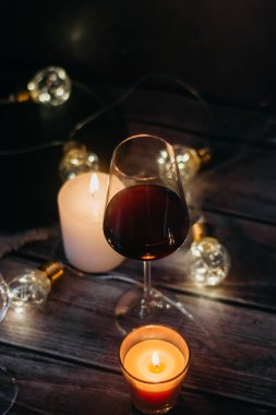 Tatil kompozisyon bardak kırmızı şarap, mumlar ve çelenk karanlık bir arka plan üzerine yapılmış