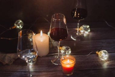 Tatil kompozisyon bardak kırmızı şarap, mumlar ve çelenk karanlık bir arka plan üzerine yapılmış