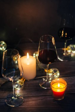Tatil kompozisyon bardak kırmızı şarap, mumlar ve çelenk karanlık bir arka plan üzerine yapılmış