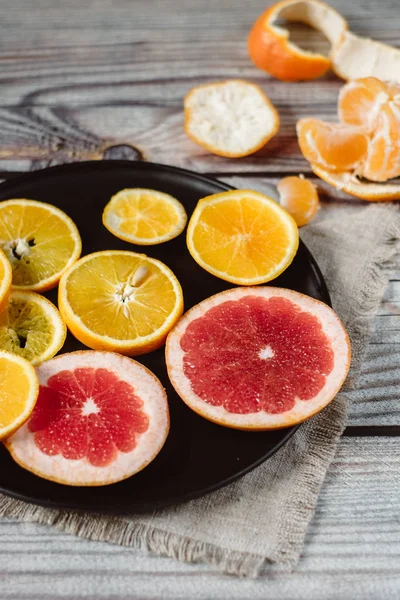 Delicious various types of citrus fruit in plates on wooden background